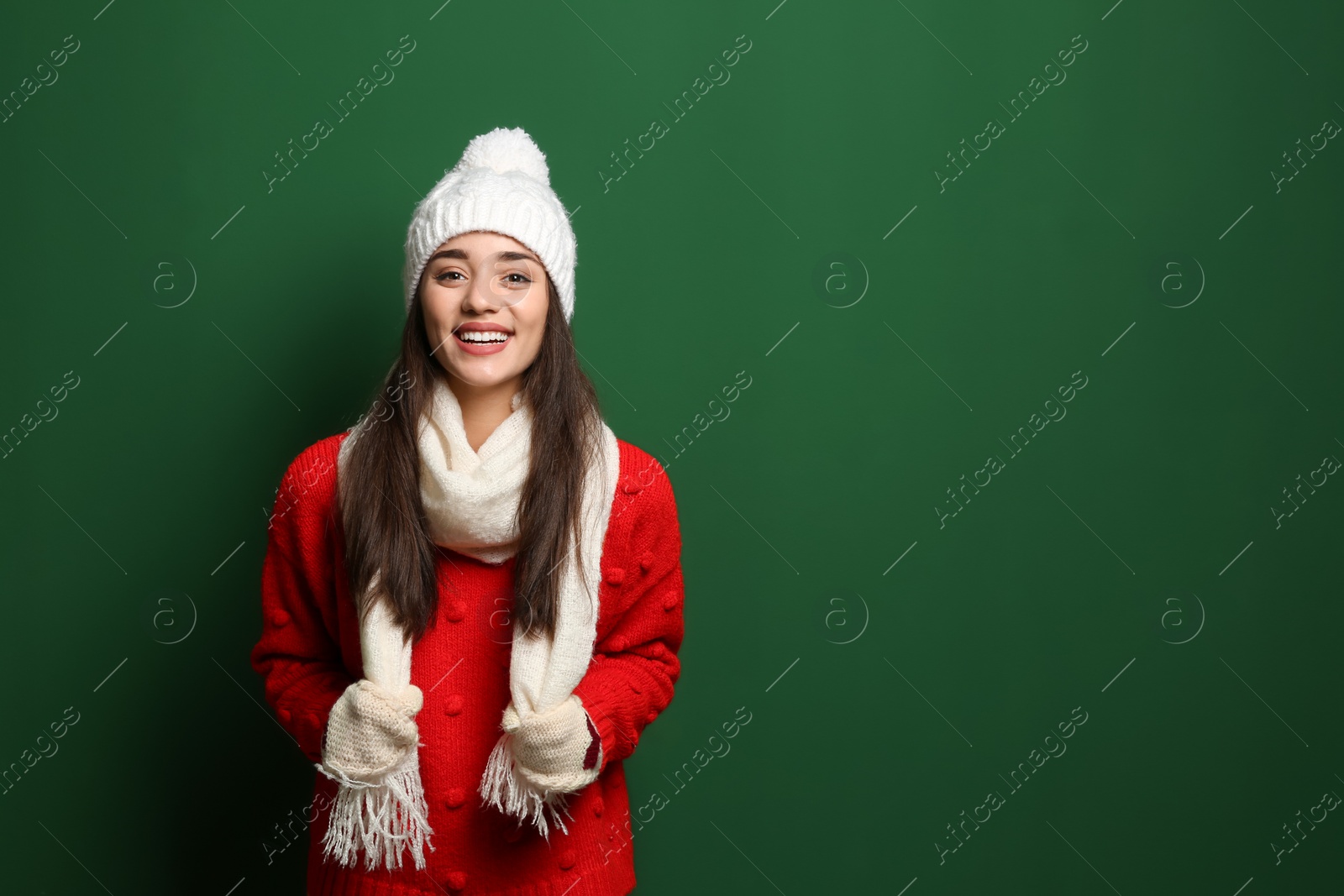 Photo of Young woman wearing warm clothes on color background, space for text. Winter season