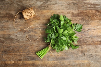 Photo of Bunch of fresh green parsley and twine on wooden background, flat lay