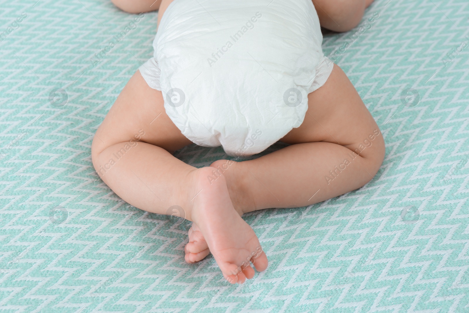 Photo of Cute little baby in diaper on bed, closeup