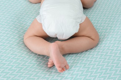 Photo of Cute little baby in diaper on bed, closeup