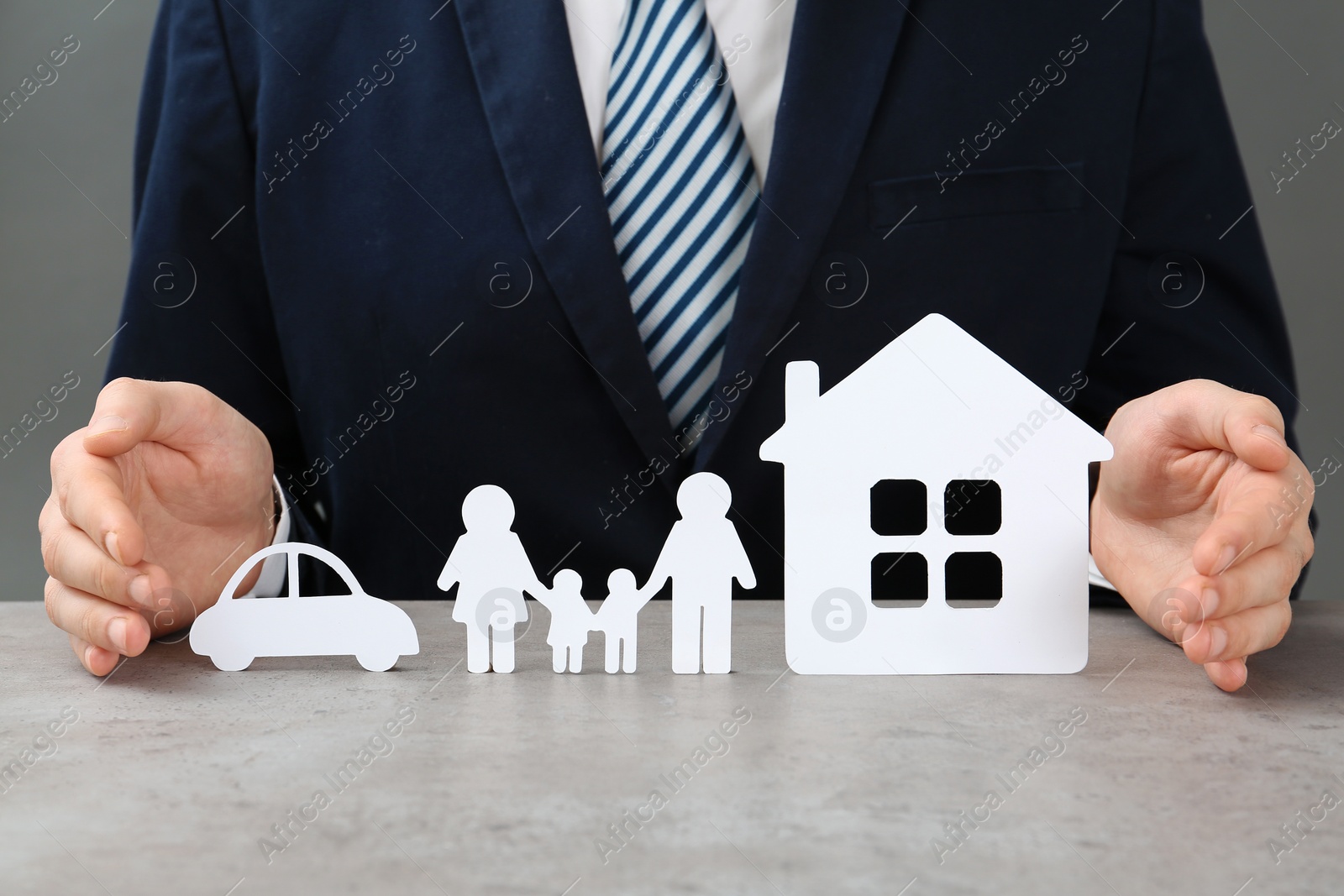 Photo of Man with cutout paper family, house and car at table, closeup. Life insurance concept