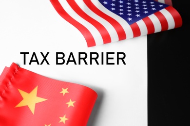 Photo of USA and China flags on paper with text TAX BARRIER, closeup