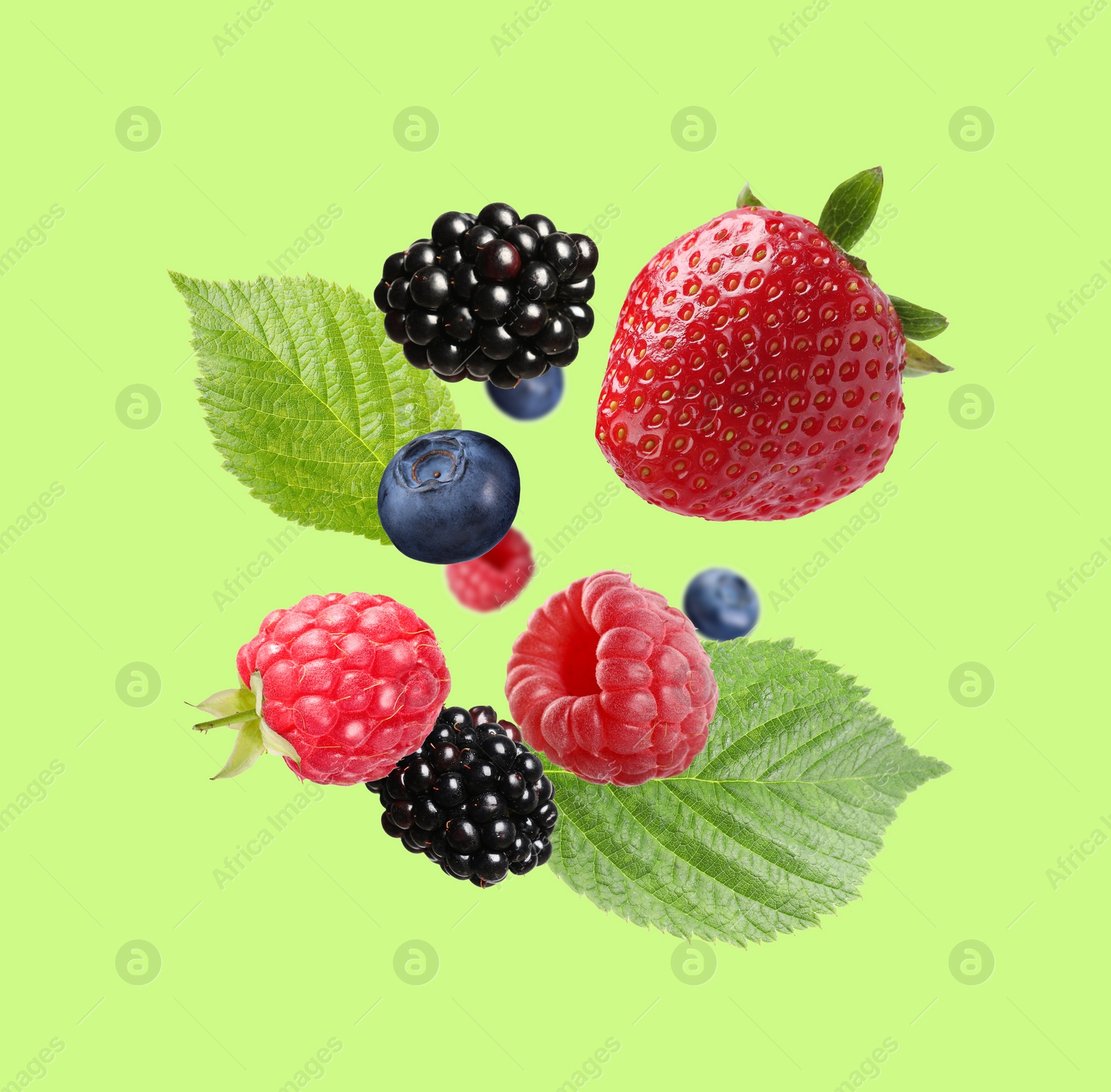 Image of Many different fresh berries falling on yellow green background