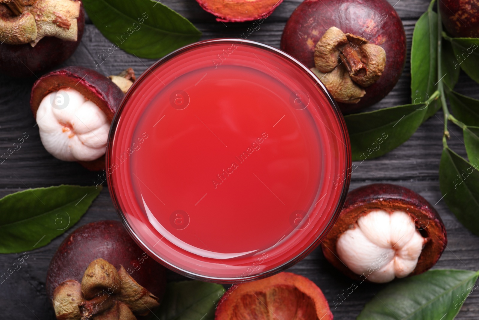 Photo of Delicious mangosteen juice and fresh fruits on black wooden table, flat lay