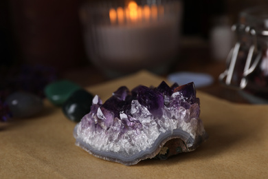 Photo of Composition with healing amethyst gemstone on table, closeup