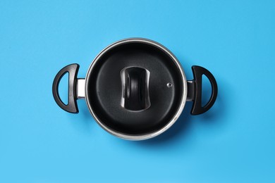 Photo of Empty pot with glass lid on light blue background, top view