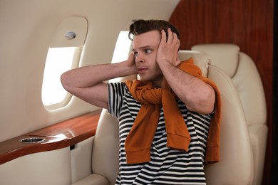Photo of Nervous young man in airplane. Aviophobia concept