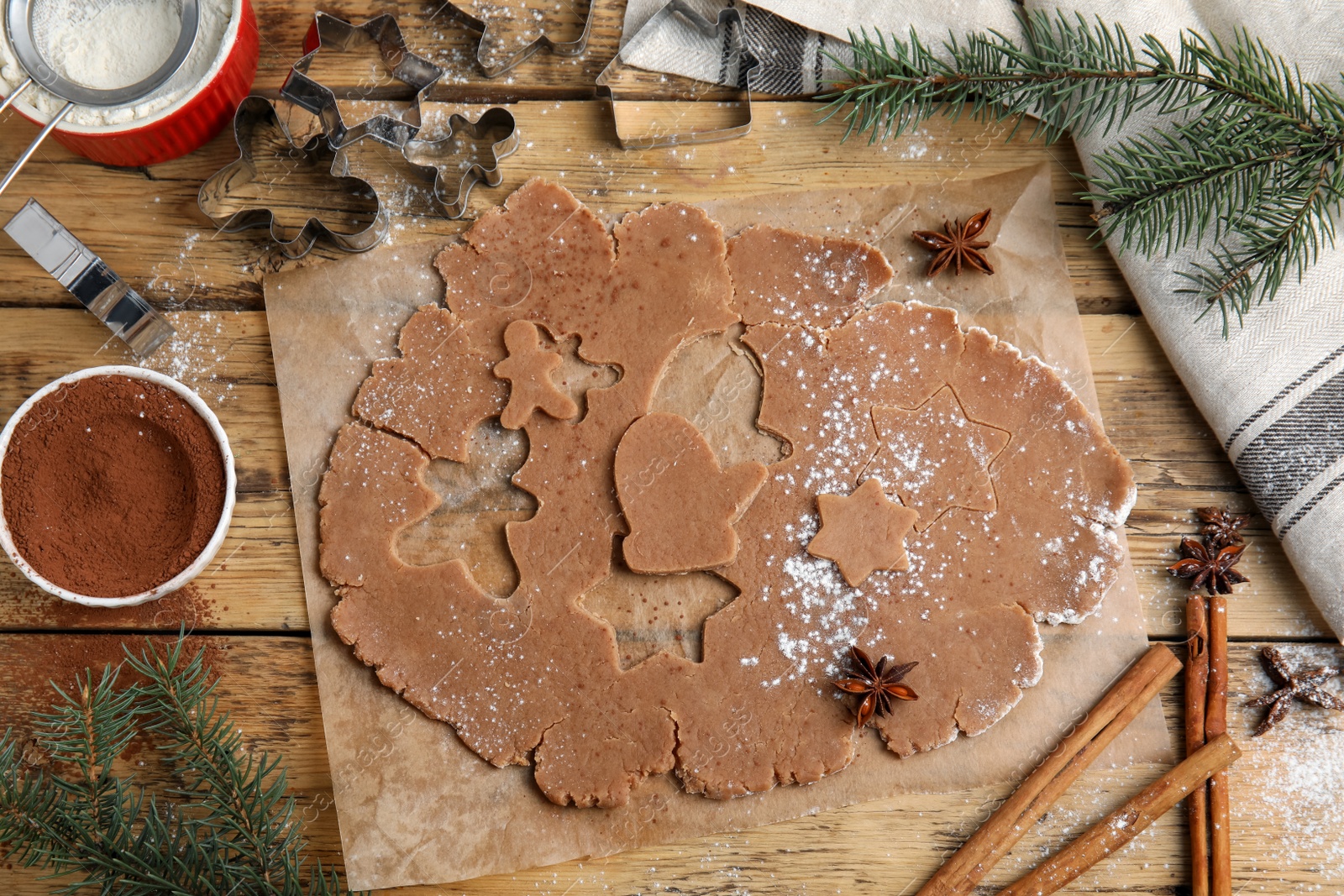 Photo of Making Christmas cookies. Flat lay composition with raw dough and cutters on wooden table