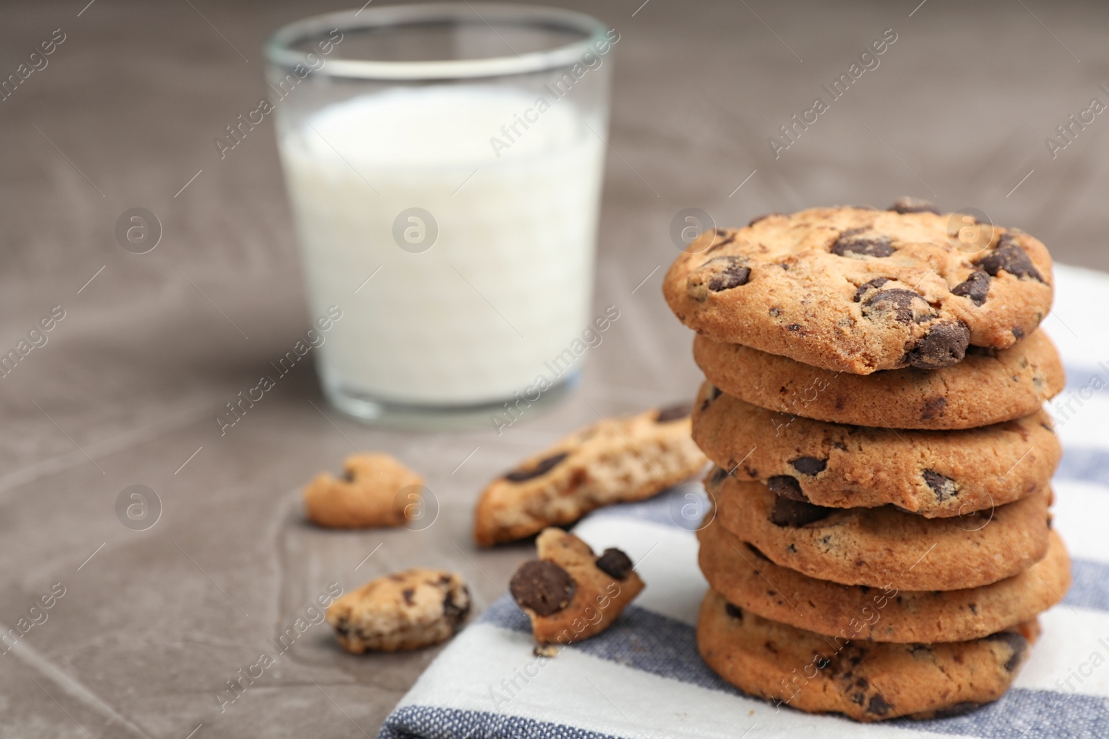 Photo of Tasty cookies with chocolate chips and glass of milk on grey table