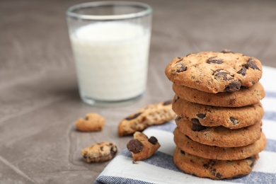 Photo of Tasty cookies with chocolate chips and glass of milk on grey table