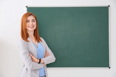 Photo of Beautiful young teacher standing near blackboard on white background