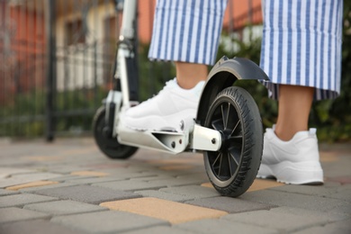 Photo of Woman riding electric kick scooter on city street, closeup