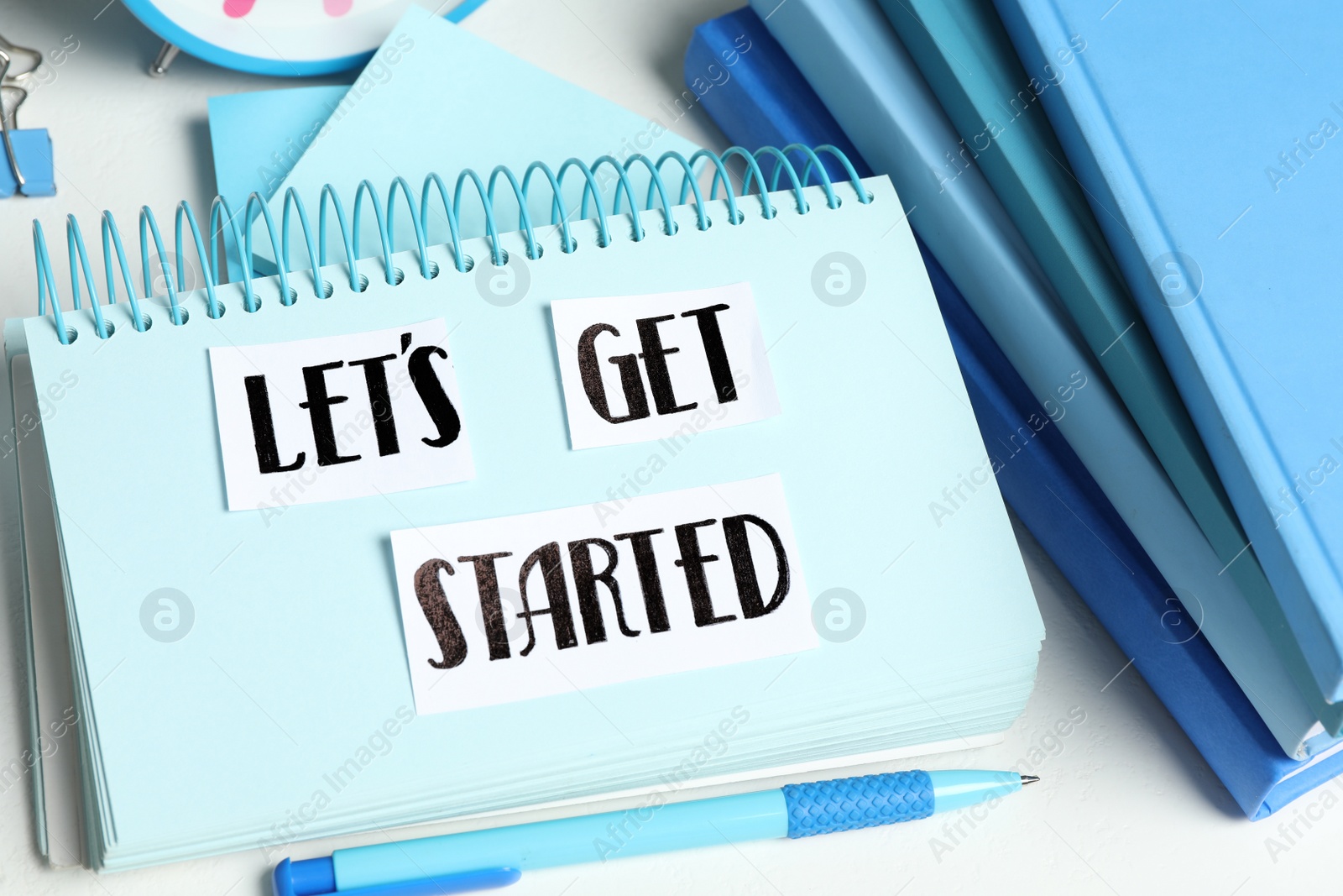 Photo of Sheets of paper with phrase Let's Get Started and stationery on white table, closeup