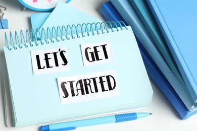 Photo of Sheets of paper with phrase Let's Get Started and stationery on white table, closeup