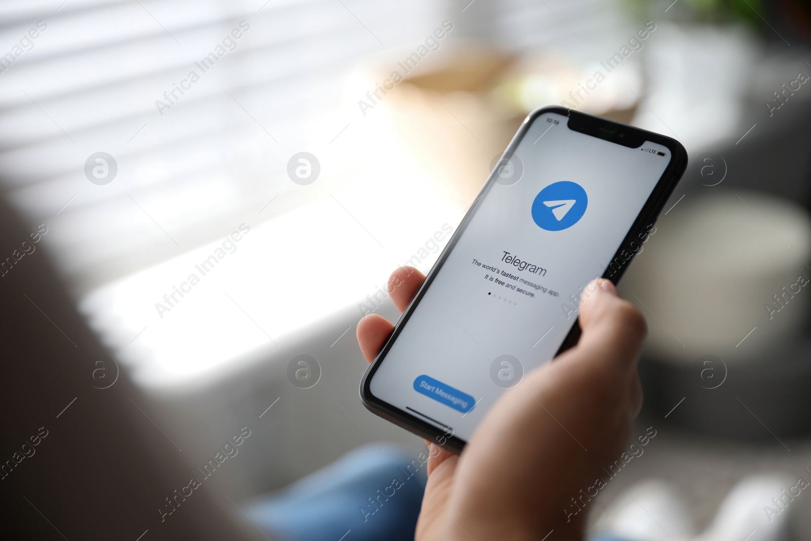 Photo of MYKOLAIV, UKRAINE - MARCH 16, 2020: Man holding iPhone 11 with Telegram app on screen indoors, closeup