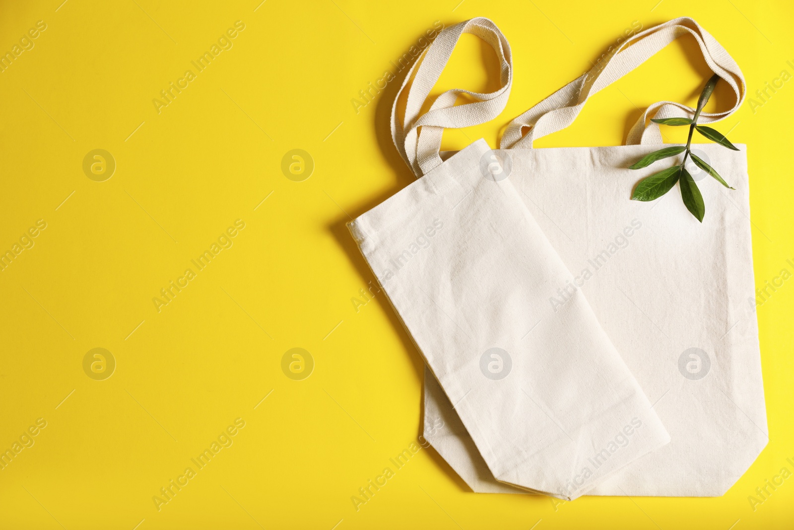 Photo of Flat lay composition with eco tote bags and space for text on color background