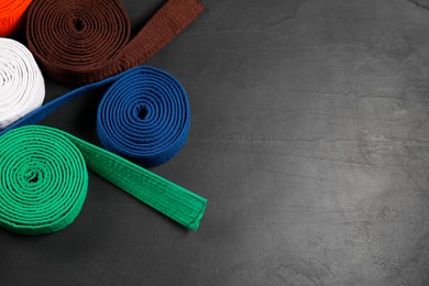 Photo of Colorful karate belts on gray background, flat lay. Space for text