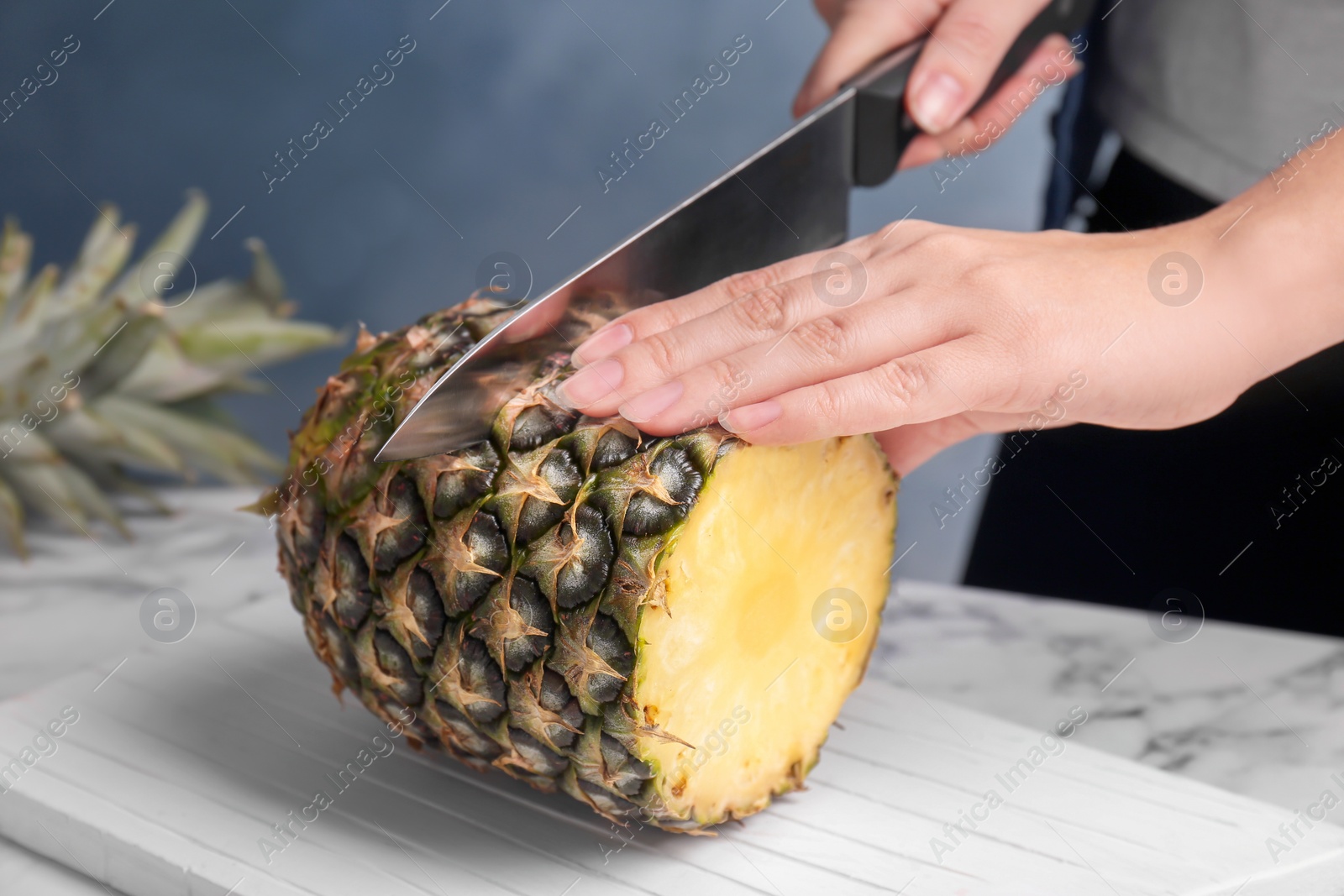 Photo of Woman cutting fresh pineapple on wooden board