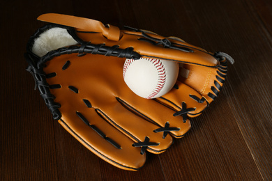 Photo of Professional leather baseball ball and glove on wooden table