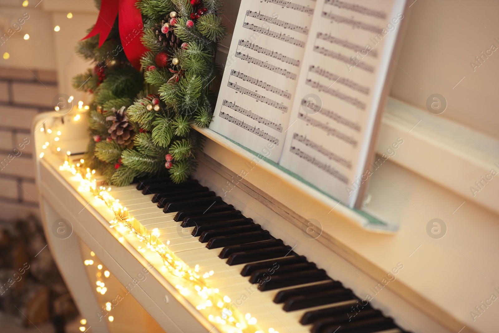 Photo of White piano with decorative wreath and note sheets closeup. Christmas music