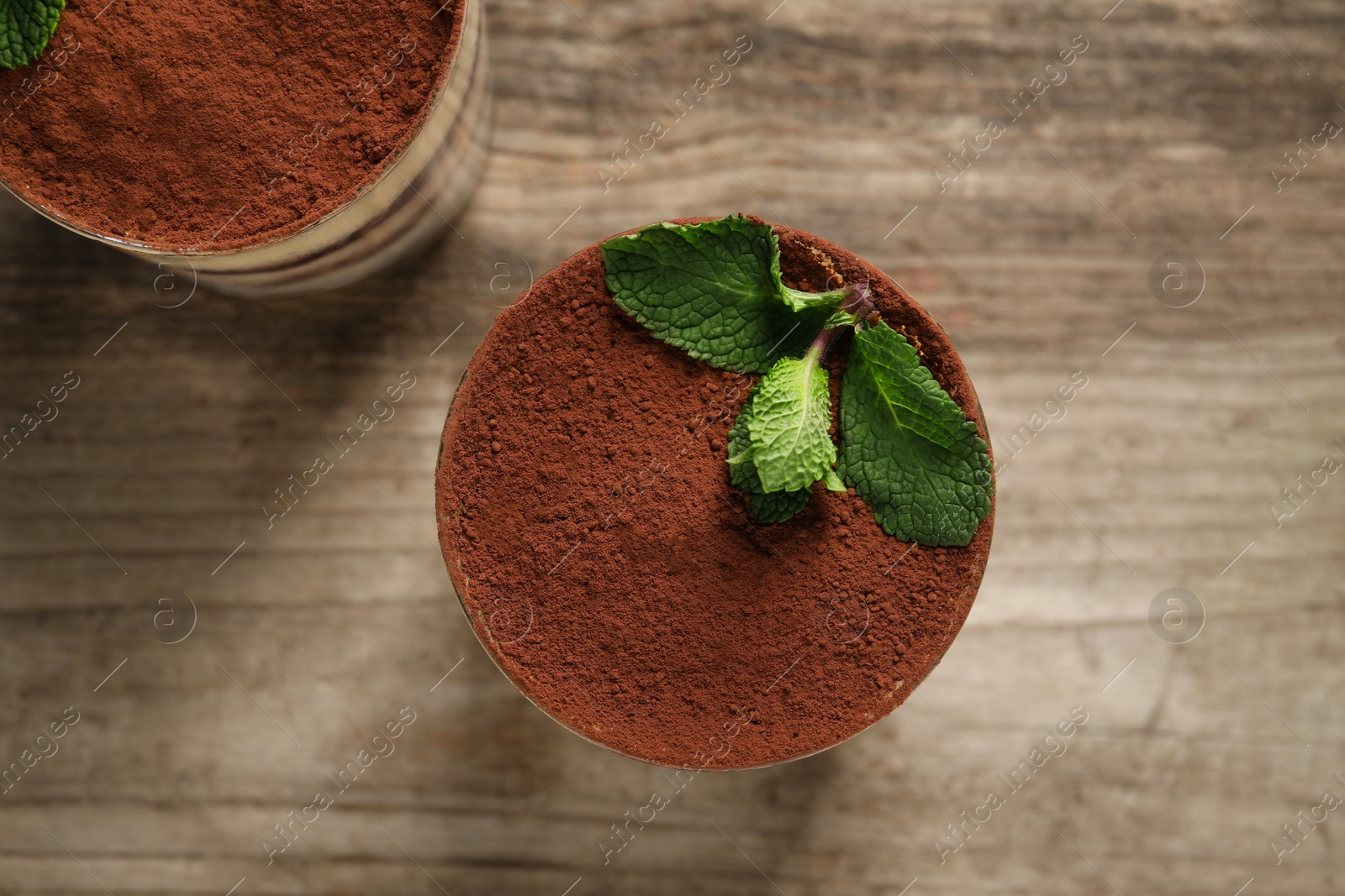 Photo of Tasty tiramisu and mint in glasses on wooden table, top view