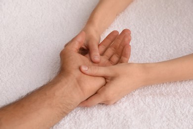 Photo of Man receiving hand massage on soft towel, closeup