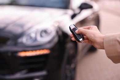 Photo of Woman holding car flip key near her vehicle outdoors, closeup