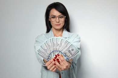 Photo of Portrait of stylish woman with money fan on light background