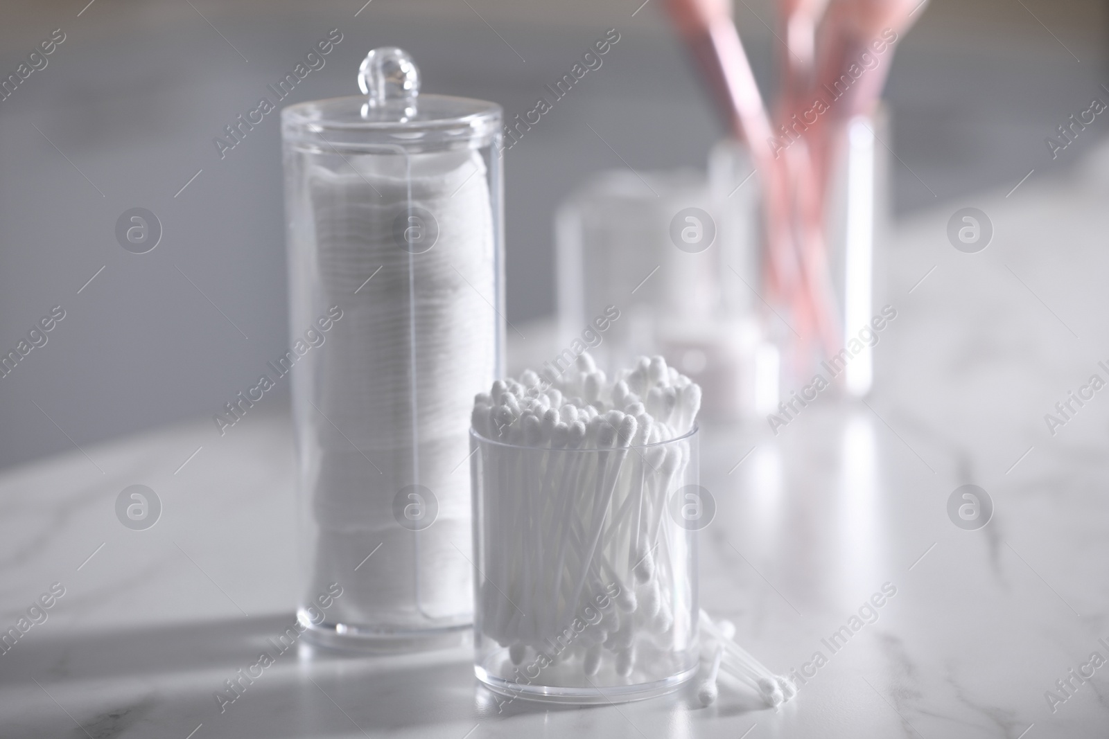 Photo of Cotton buds and pads in transparent holders on light table