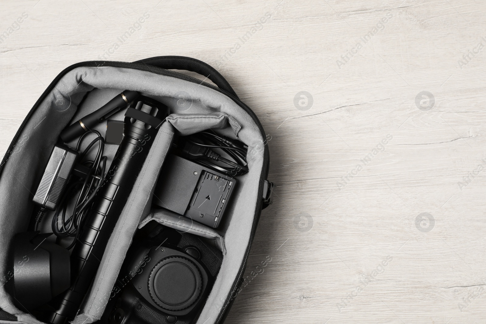 Photo of Professional photography equipment in backpack on wooden table, top view. Space for text