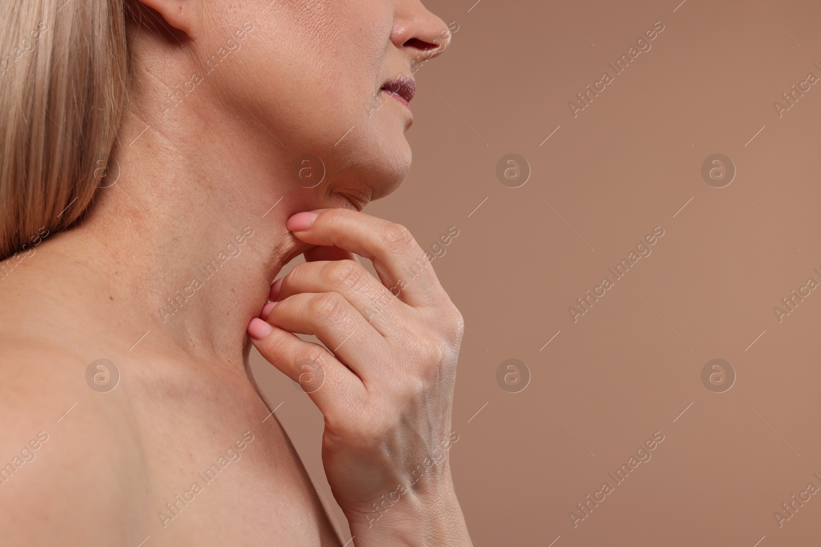 Photo of Mature woman touching her neck on beige background, closeup. Space for text