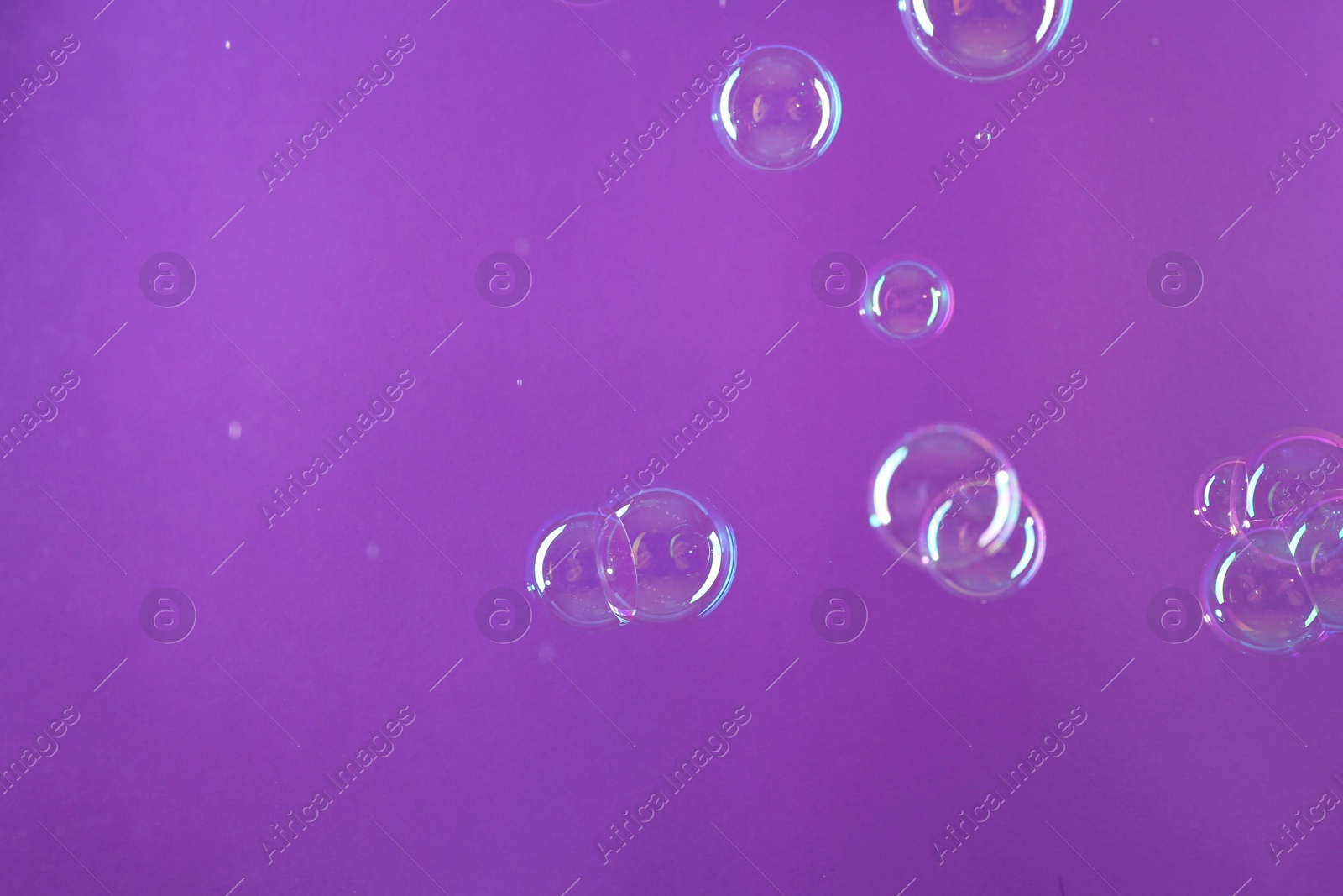 Photo of Beautiful transparent soap bubbles on violet background, space for text