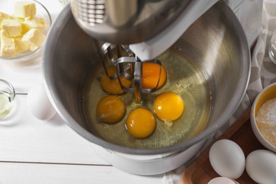Making dough. Raw eggs in bowl of stand mixer on white table, closeup