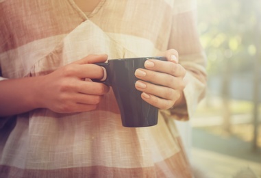 Photo of Woman holding elegant cup indoors, closeup view