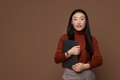 Photo of Portrait of smiling woman with laptop on brown background. Space for text