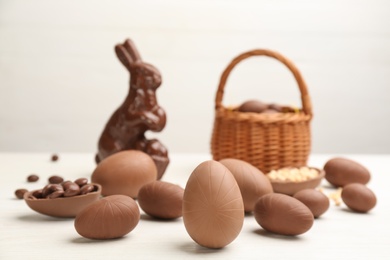 Sweet chocolate eggs on white wooden table