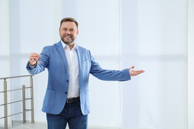 Male real estate agent holding key in new apartment