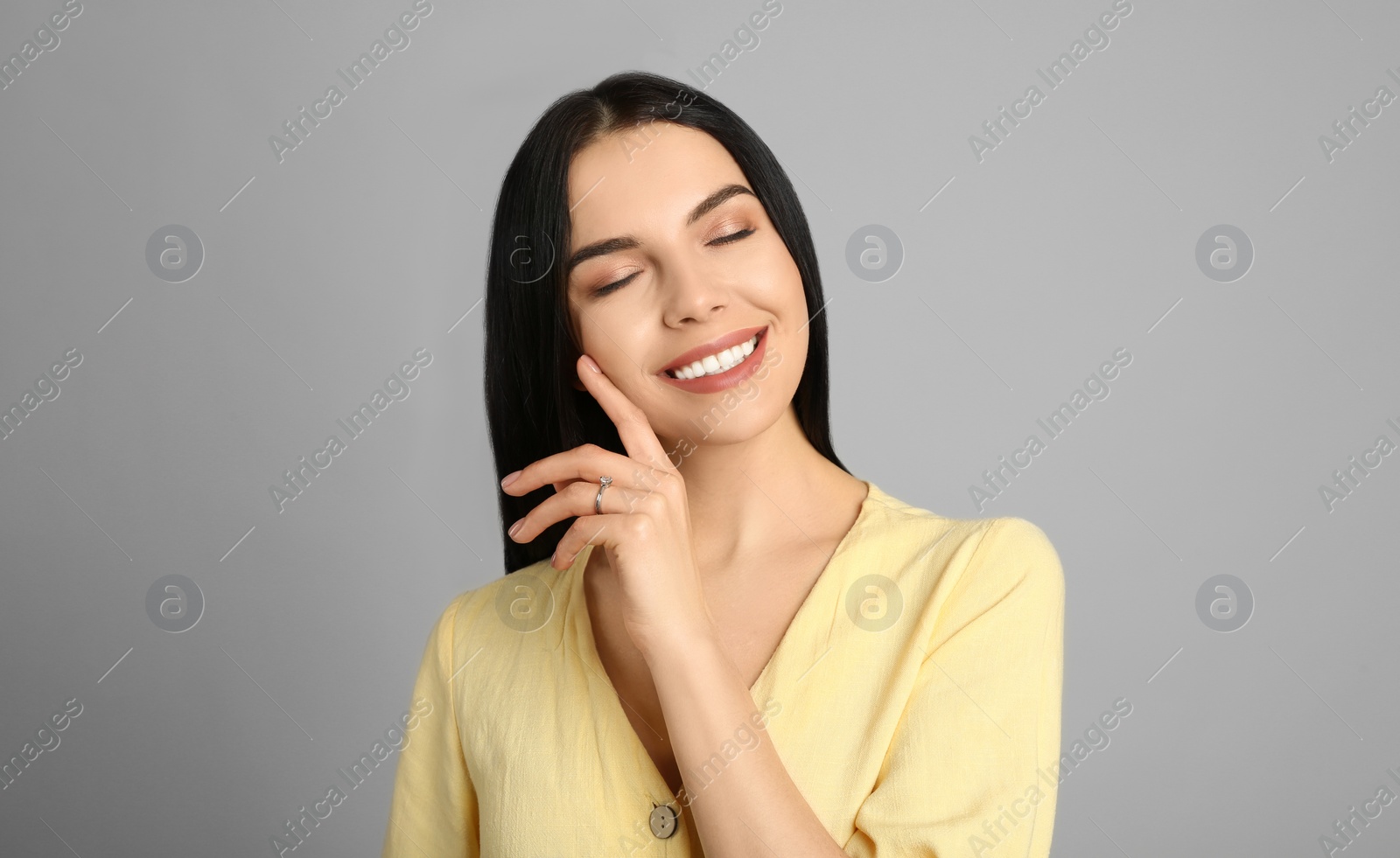 Photo of Happy young woman wearing beautiful engagement ring on grey background