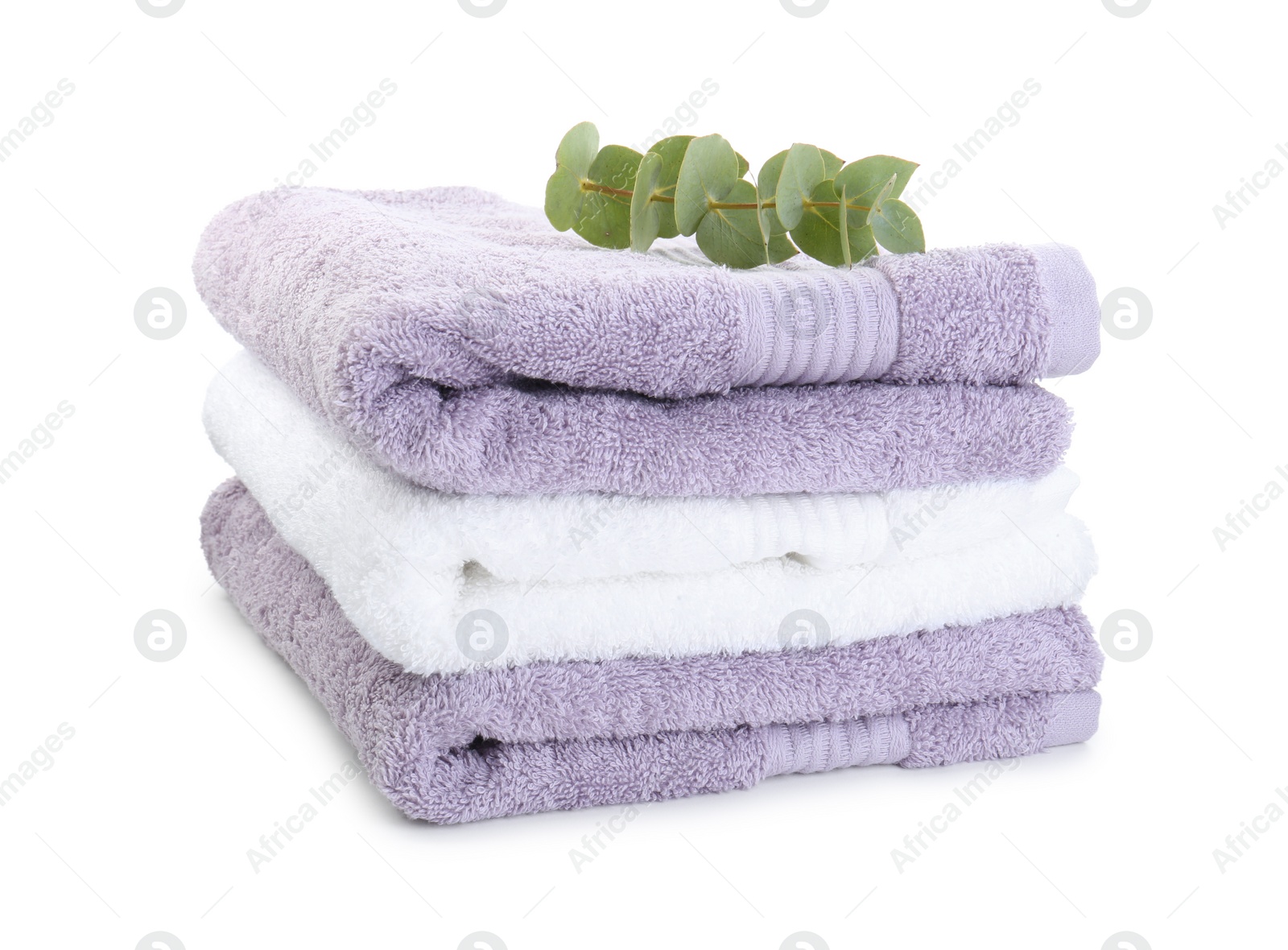 Photo of Stack of different folded terry towels and eucalyptus branch isolated on white