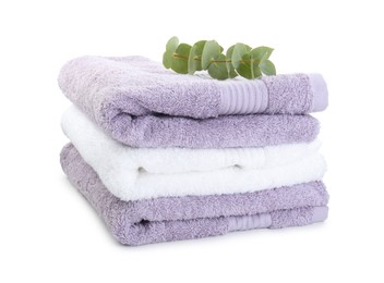 Photo of Stack of different folded terry towels and eucalyptus branch isolated on white