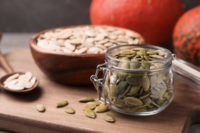 Photo of Shelled raw pumpkin seeds in jar on wooden board