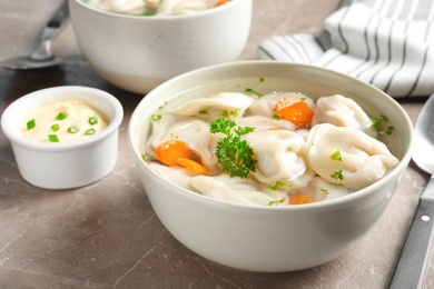 Photo of Bowl of tasty dumplings in broth served on table