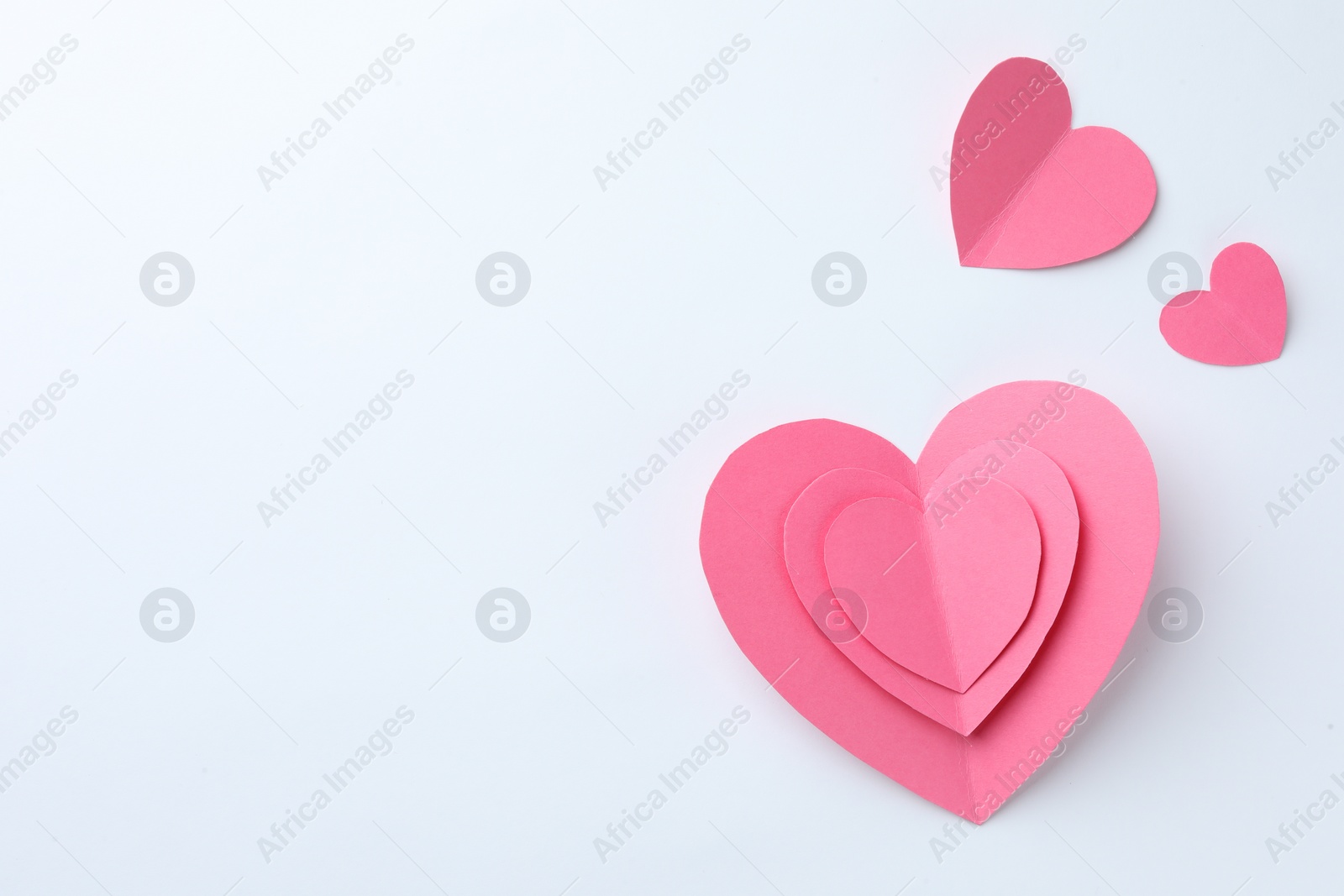 Photo of Pink paper hearts on white background, flat lay. Space for text