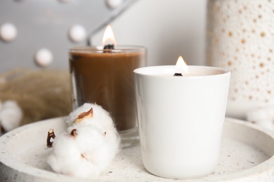 Photo of Burning candles with wooden wicks and cotton flower on tray