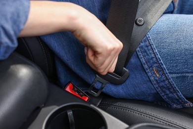 Woman fastening safety seat belt inside modern car