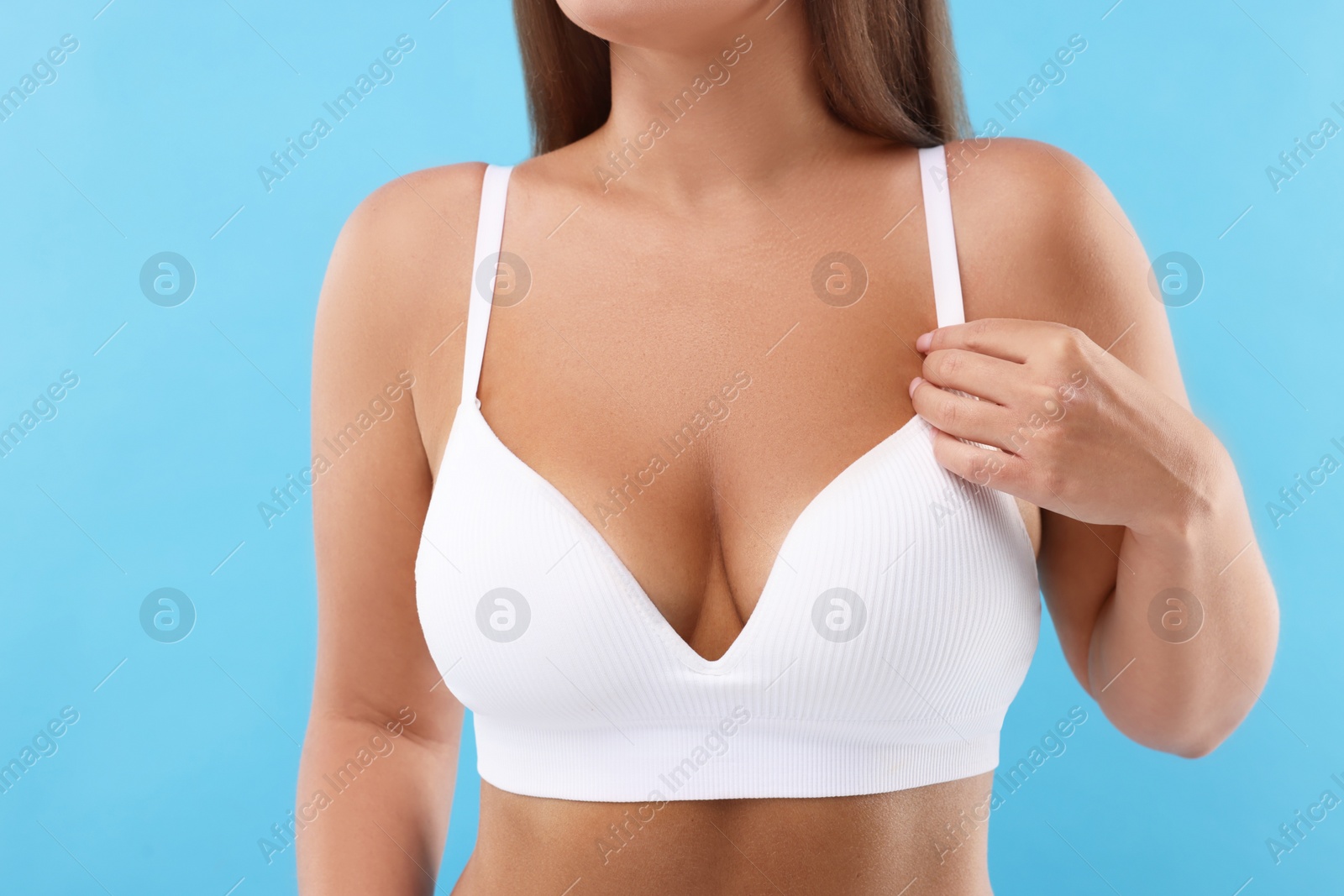 Photo of Woman with beautiful breast on light blue background, closeup