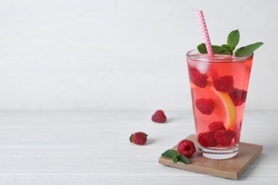 Photo of Delicious raspberry lemonade made with soda water and ingredients on white wooden table. Space for text