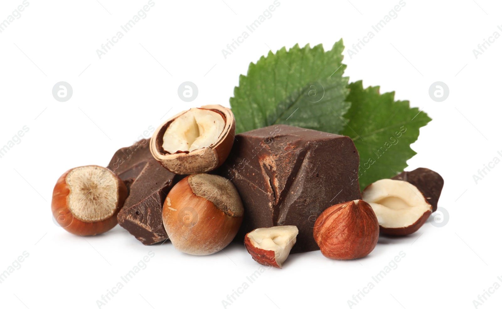 Photo of Delicious chocolate chunks with hazelnuts and green leaves on white background