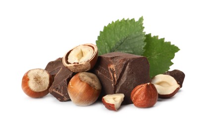 Photo of Delicious chocolate chunks with hazelnuts and green leaves on white background