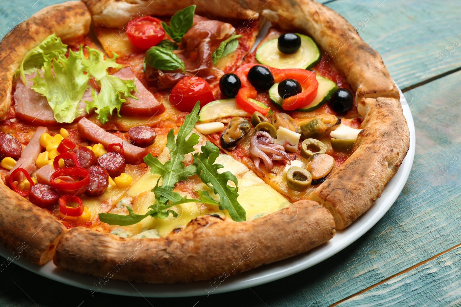 Photo of Slices of different delicious pizzas on blue wooden table, closeup